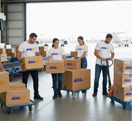 Equipo de operarios de Ágilex con camisetas blancas y logo corporativo moviendo cajas y pallets en un hangar aeroportuario con aviones de carga al fondo, representando la flexibilidad operativa.