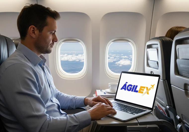 Hombre de negocios utilizando una laptop con el logo de Ágilex a bordo de un avión, supervisando su inventario y envíos internacionales en tiempo real a través de la plataforma digital.