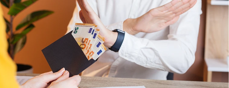 Una persona hace un gesto de rechazo con las manos ante un sobre con billetes de euro, representando el temor a la inseguridad y la falta de confianza en los cobros internacionales tradicionales.