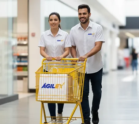 Dos especialistas de Ágilex sonrientes empujando un carrito amarillo con bolsas de compras de la marca en un entorno comercial, representando el éxito de negocios e-commerce.