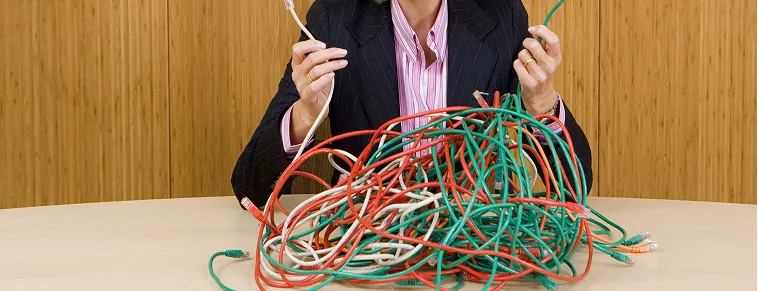 Profesional gestionando cables enredados, simbolizando la complejidad de los procesos logísticos.